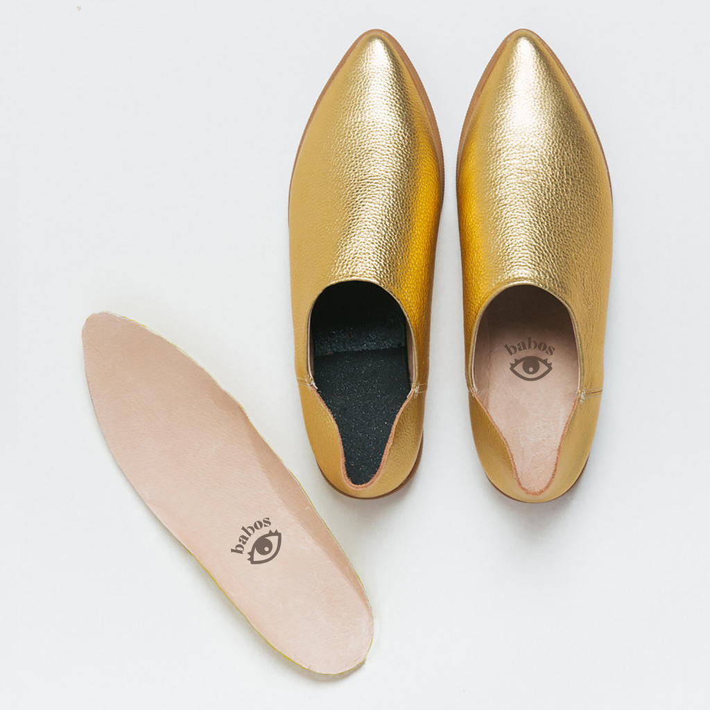 Restorative footbed insoles next to a pair of gold leather babouche sneakers from Babos.
